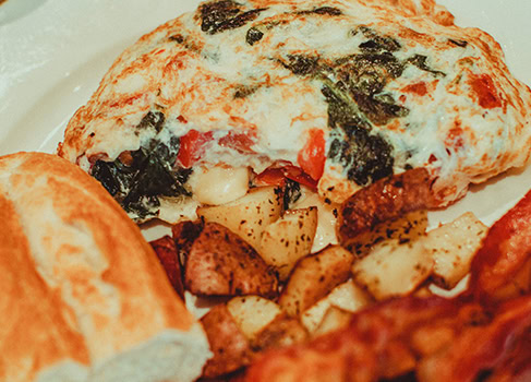 Delicious stuffed bread roll with cheese, vegetables, and herbs, served with crispy potatoes.